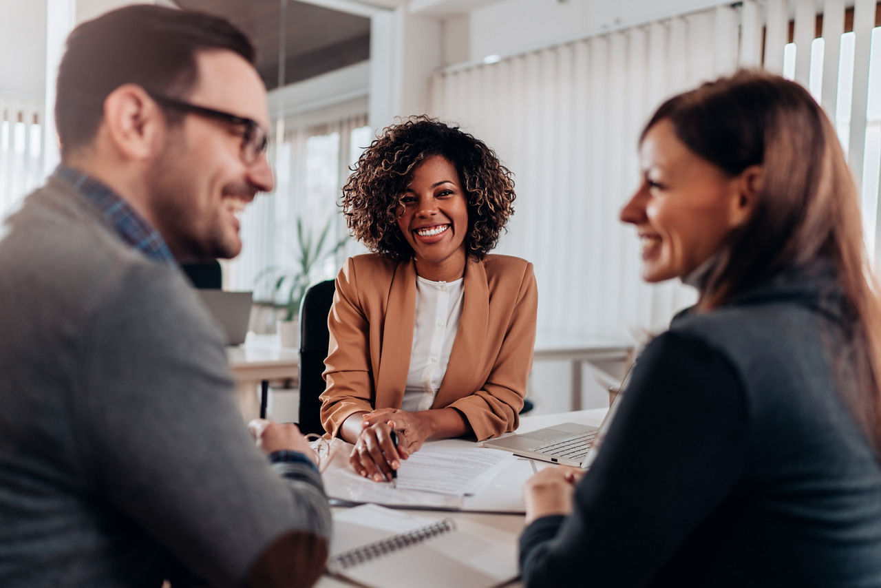 Couple consulting with a female financial manager at the bank about real estate loan